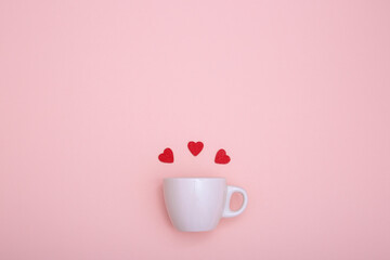 Coffee cup and red wooden hearts on a red background. The concept of Valentine's day, love, dating and wedding. Symbol of a romantic gift or marriage proposal. Copy space, minimalism.