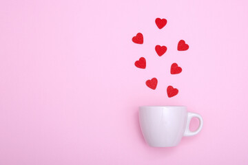 Coffee cup and red wooden hearts on a pink background. The concept of Valentine's day, love, dating and wedding. Symbol of a romantic gift or marriage proposal. Copy space, minimalism.