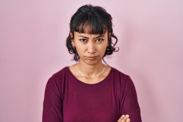Young beautiful woman standing over pink background skeptic and nervous, disapproving expression on face with crossed arms. negative person.