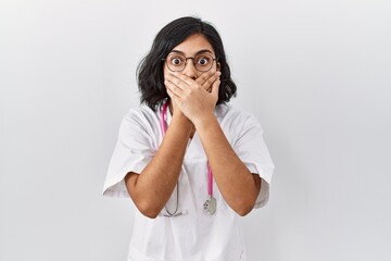 Young hispanic doctor woman wearing stethoscope over isolated background shocked covering mouth with hands for mistake. secret concept.