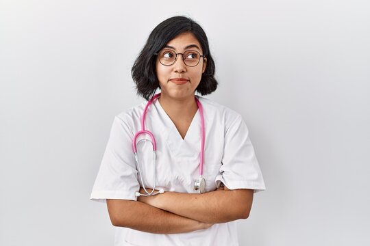 Young hispanic doctor woman wearing stethoscope over isolated background smiling looking to the side and staring away thinking.