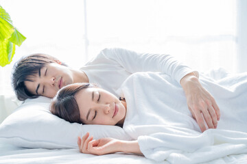 Obraz na płótnie Canvas 寝室のベッドで眠る若い夫婦-朝