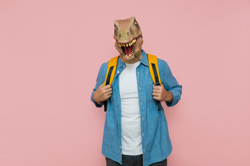 Man with backpack and lizard mask on pink background.