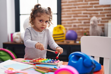 Adorable caucasian girl playing xylophone standing at kindergarten