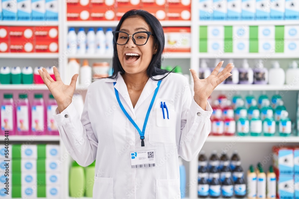 Wall mural hispanic woman working at pharmacy drugstore celebrating victory with happy smile and winner express