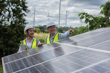 engineers male and female discussing against solar cell panel on wind turbine farm. © ENGINEER - STUDIO