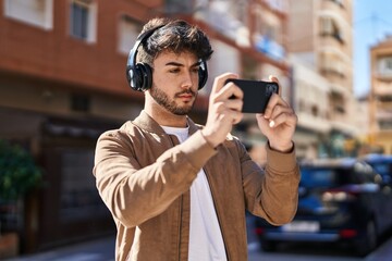 Young hispanic man playing video game at street