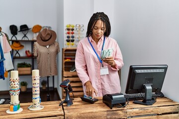 Young african american woman holding dollars banknotes at clothing store