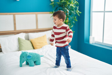 Adorable toddler smiling confident standing on bed at bedroom