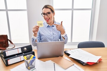 Young hispanic business woman at the office calculating taxes smiling happy pointing with hand and...
