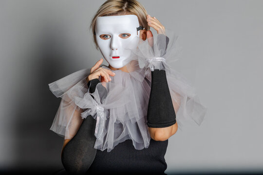 Woman in white theater mask and harlequin collar on gray background. Fancy dress, masquerade clothes. High quality photo