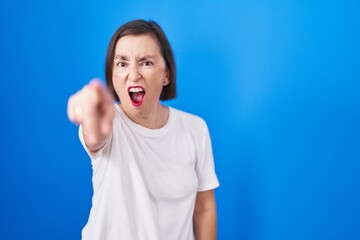 Middle age hispanic woman standing over blue background pointing displeased and frustrated to the camera, angry and furious with you
