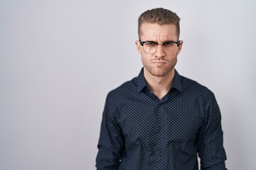 Young caucasian man standing over isolated background skeptic and nervous, frowning upset because of problem. negative person.