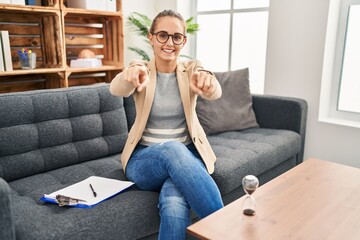Obraz premium Young woman working at consultation office pointing to you and the camera with fingers, smiling positive and cheerful