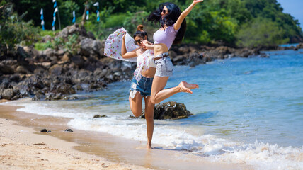 Naklejka premium Two Beautiful young women happy jumping together on the beach. Vacation trip summer holiday. friends holding hands jump enjoy life Vacation trip summer holiday.