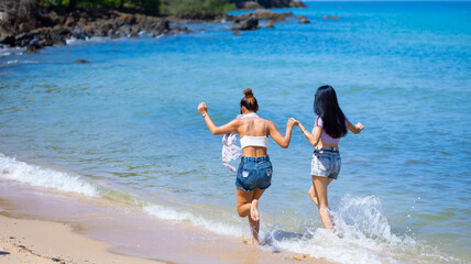 Two Beautiful young women happy running together on the beach. Vacation trip summer holiday. friends holding hands running enjoy life Vacation trip summer holiday.