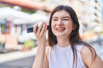 Young caucasian woman smiling confident listening audio message by the smartphone at street