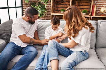 Family doing tickle to son sitting on sofa at home
