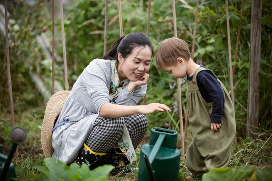 Mother and toddler son with watering can in garden