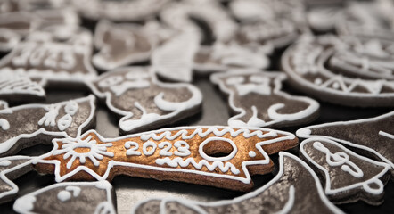 Closeup of New Year gingerbread for good luck in 2023 and white decorated Xmas pastry. Fragrant Christmas sweets with beautiful golden baked cookie in Bethlehem star shape with dark blurry background.