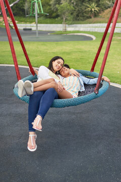 Portrait happy mother and daughter on playground trampoline swing