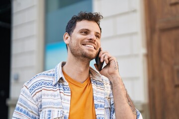 Young hispanic man smiling confident talking on the smartphone at street