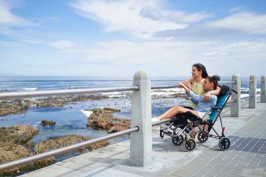 Mother and disabled daughter in pushchair at ocean boardwalk