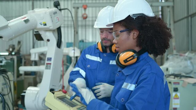Young female engineers trainee are doing apprenticeships and learning from seniors who give advice. operation of robotic welding machine