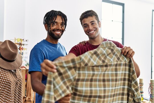 Two men friends choosing clothes holding shirt at clothing store