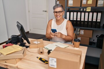 Middle age woman ecommerce business worker using smartphone at office