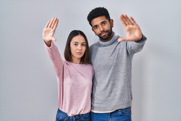 Young hispanic couple standing together doing frame using hands palms and fingers, camera perspective