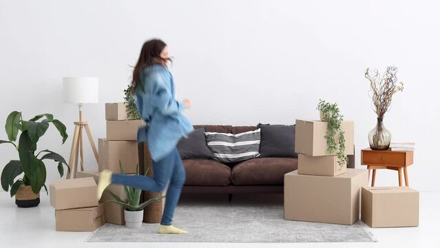 Happy young woman celebrate moving relocation day enjoy new rented apartment. Have fun concept
