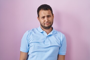 Hispanic man standing over pink background depressed and worry for distress, crying angry and afraid. sad expression.