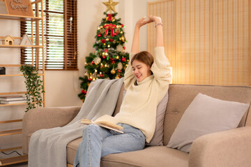 Young asian woman wearing sweater and stretching with raise arms up after reading a book while sitting