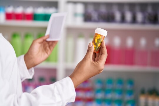 African american woman pharmacist holding pills bottle and prescription at pharmacy