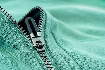 Close-up of the zipper on the green clothing. Zipper with lock. Fabric with zipper