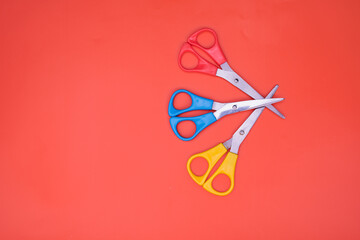 three brightly colored pairs of  craft scissors isolated on an orange background