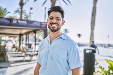 Young hispanic man smiling happy standing at the promenade.