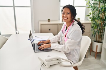 Obraz premium Young chinese woman wearing doctor uniform using laptop at clinic