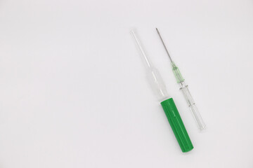 IV catheter with green needle sheath placed on white background.