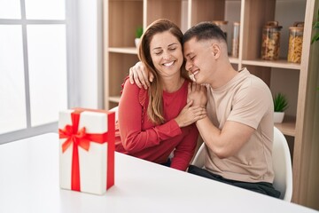 Man and woman mother and son sitting on table with gift at home