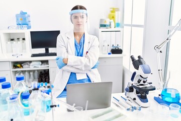 Young hispanic woman wearing scientist uniform skeptic and nervous, disapproving expression on face with crossed arms. negative person.