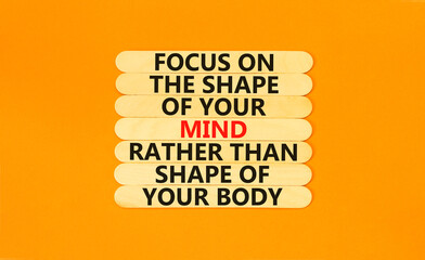 Mind or body symbol. Concept words Focus on the shape of mind rather than shape of your body on wooden sticks. Beautiful orange table orange background copy space. Business mind or body concept.