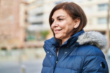 Middle age woman smiling confident looking to the side at street