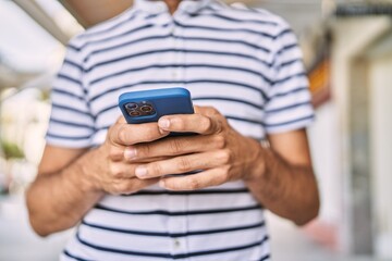 Young hispanic man using smartphone at street