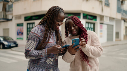 Two african american friends smiling confident using smartphone at street