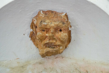 old gargoyle head carved into a wall