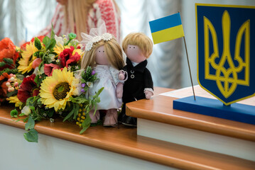 Ukrainian flag and coat of arms with fabric with texture of pixeled camouflage. Cloth with camo pattern in grey, brown and green pixel shapes with Ukrainian trident sign in the registry office
