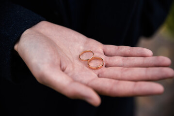 Groom holding wedding rings in hand. Two wedding rings on the floor with contrast wedding rings on floor, on ground, on piano, in hand