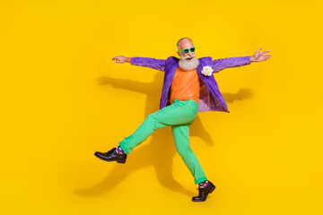 Fototapeta na wymiar Full length photo of cheerful excited guy dressed violet velvet jacket hands sides walking disco isolated yellow color background